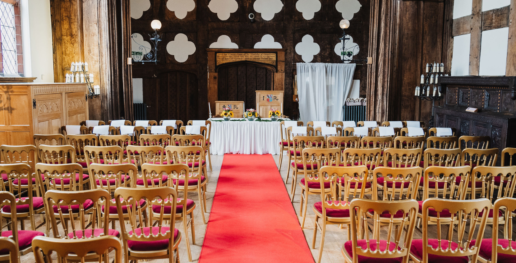 Wedding set up in the Great Hall with brown wooden chairs and a red carpet