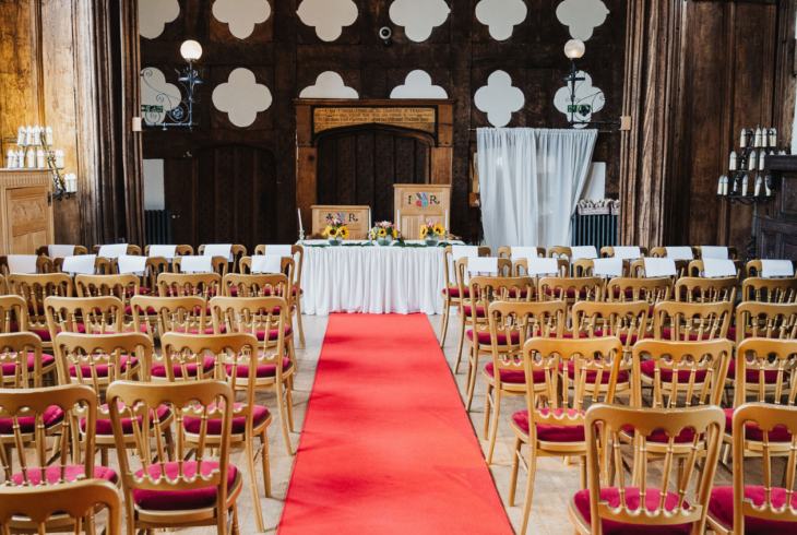 Wedding set up in the Great Hall with brown wooden chairs and a red carpet