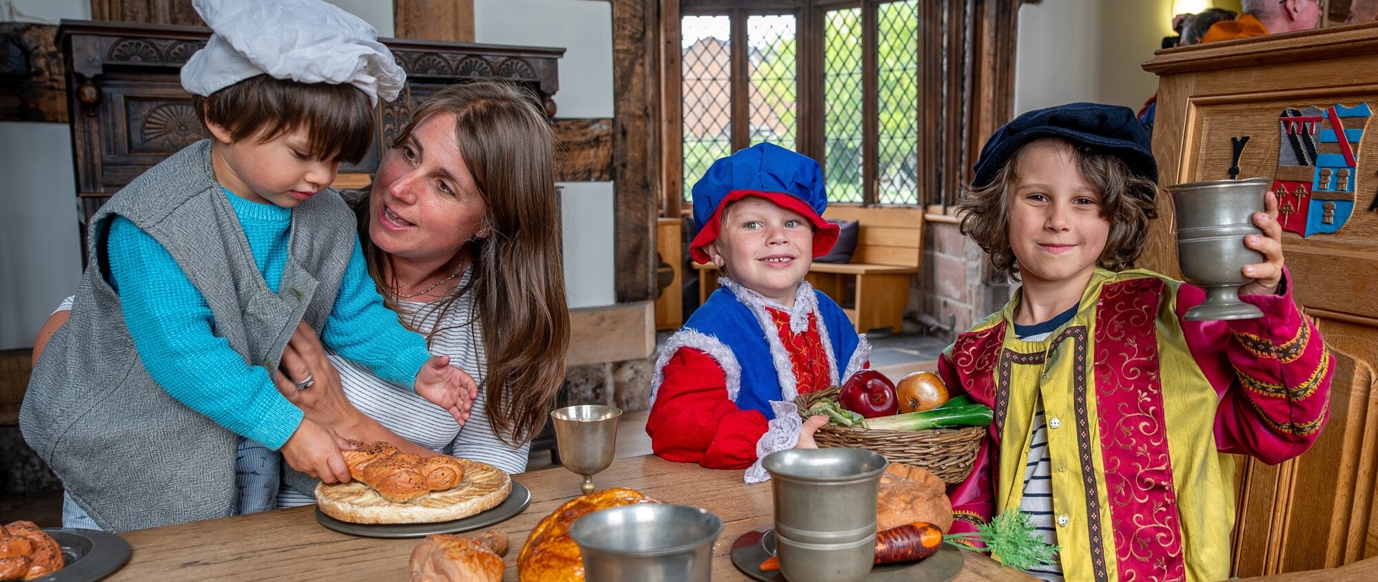 Three childern and their mum are dressed as Tudors at a banqueting table