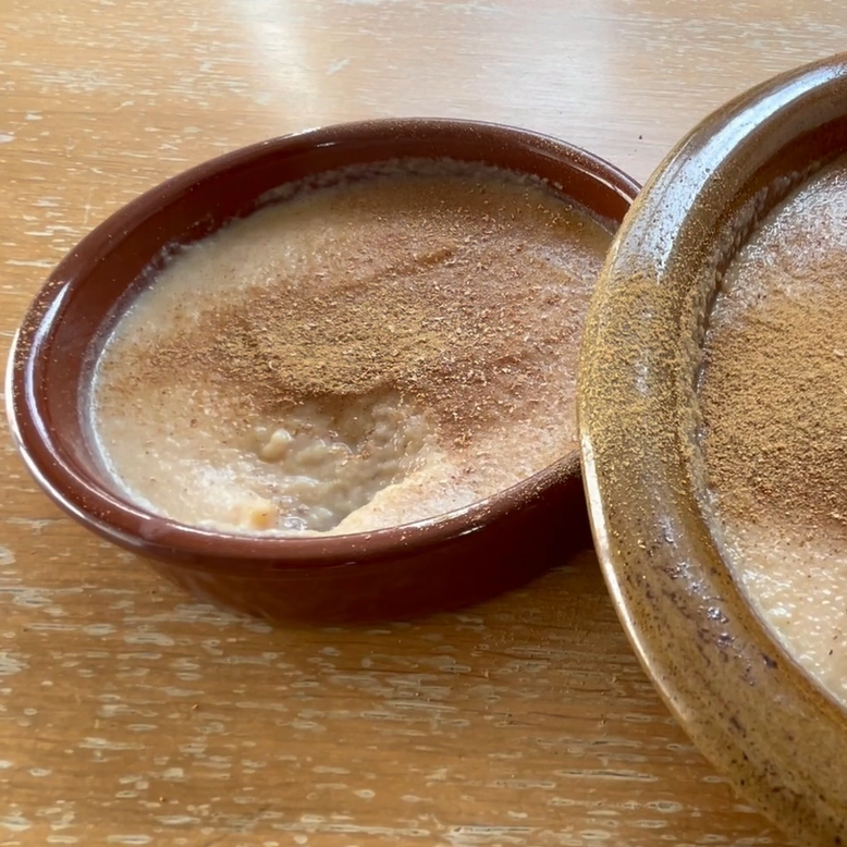 An earthen ware bowl, containing an apple mousse sprinkled with spices.